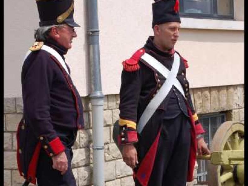 Napoleonic Bivouac в Люксембурге: два солдата в мундирах 1812 года у пушечного колеса