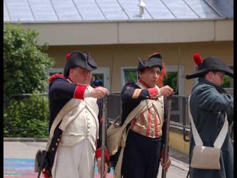 Napoleonic Bivouac в Люксембурге: три солдата в мушкетерских костюмах у здания с металлической крышей