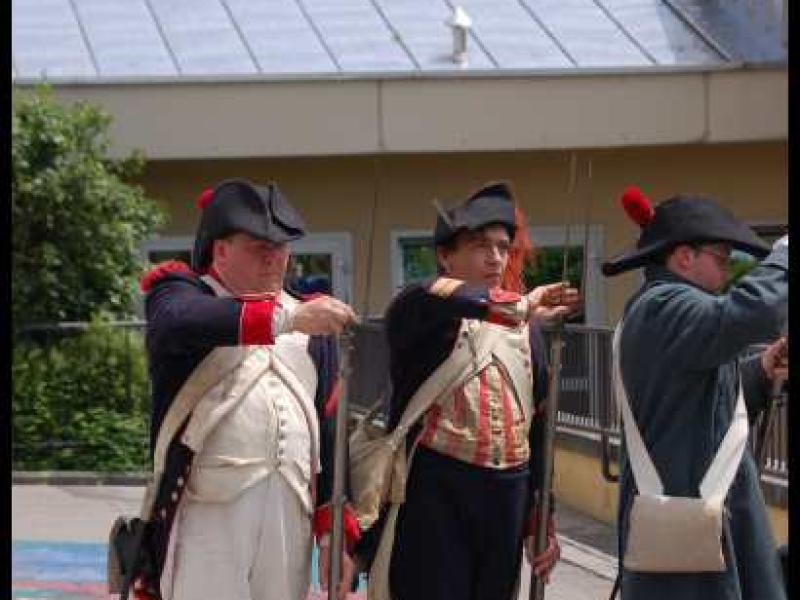 Napoleonic Bivouac в Люксембурге: три солдата в исторических костюмах у здания с металлической крышей