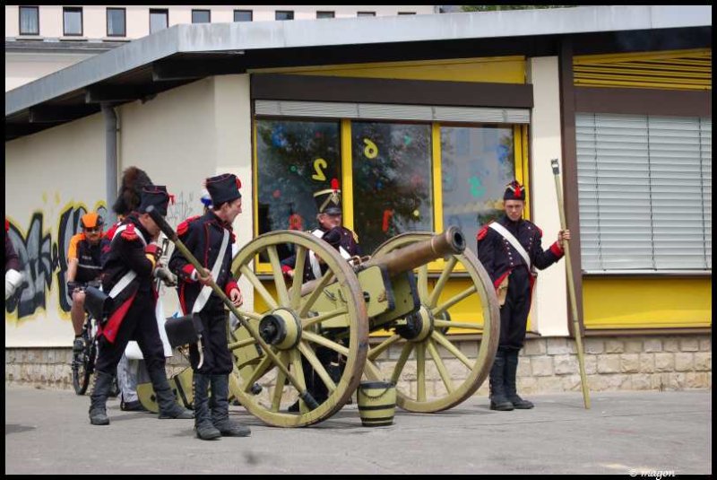 Napoleonic Bivouac в Люксембурге: солдаты с пушкой у здания с желтыми окнами