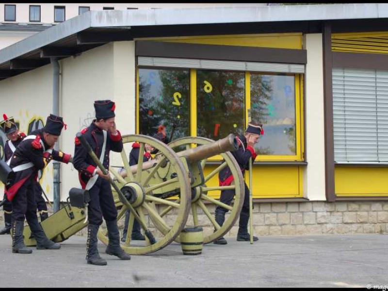 Napoleonic Bivouac в Люксембурге: солдаты у пушки у здания с желтыми окнами