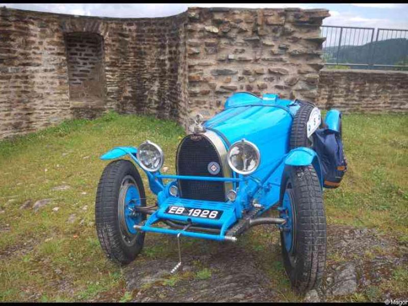 Синий ретро-автомобиль Bugatti EB 1928 у старинной каменной стены