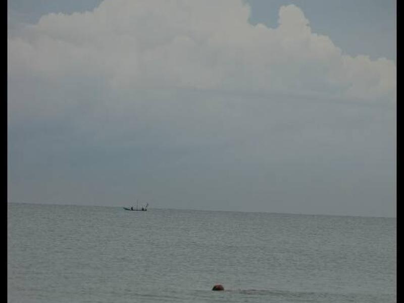 Куантан, Малайзия: лодка на горизонте и буй в спокойной воде