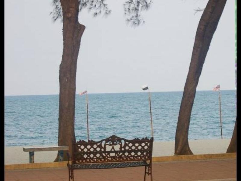 Куантан, Малайзия: кованая скамья у моря между двумя пальмами