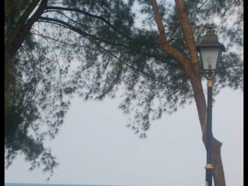 Куантан, Малайзия: фонарь у пляжа с двумя фигурами у воды