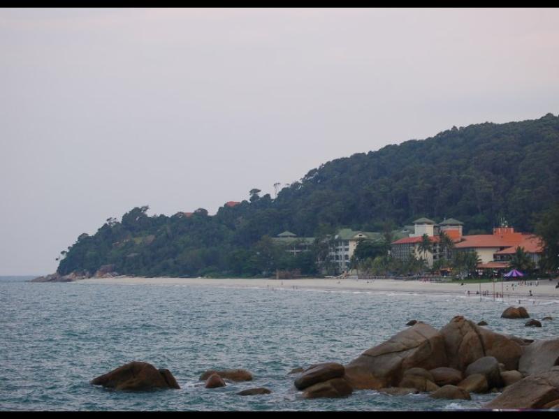 Пляж в Куантане: скалы, отель и зелёный холм у моря