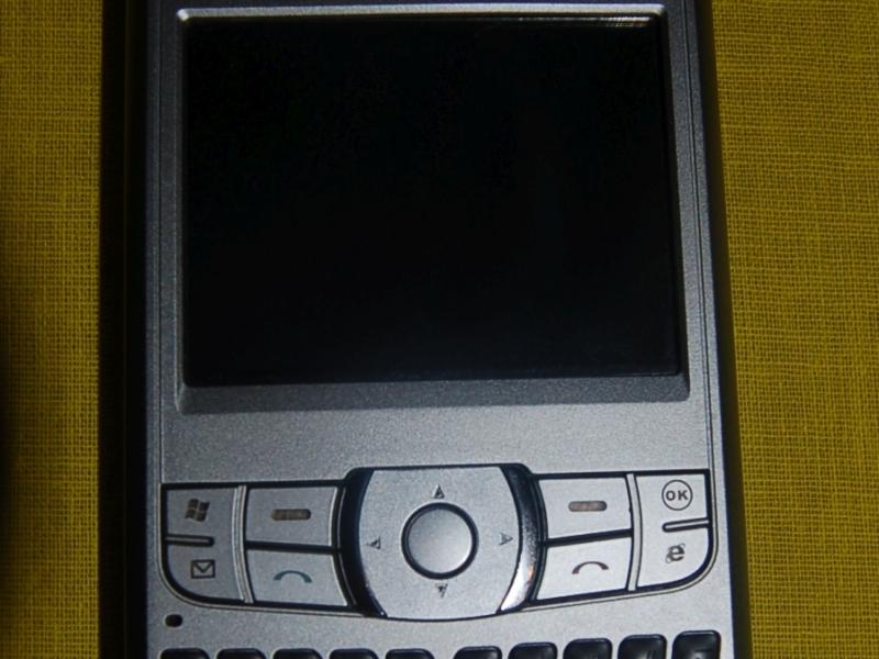 Orsio P745 на жёлтом ткани: серебристый телефон с физической клавиатурой и Windows Mobile