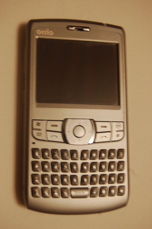 Orsio P745 на стене в тёплом свете — серебристый гаджет эпохи Windows Mobile