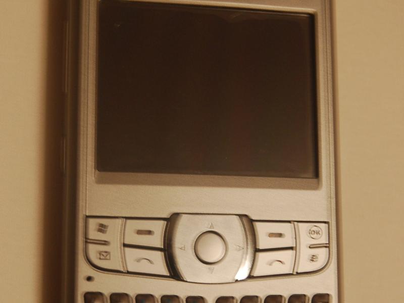 Orsio P745 на стене в тёплом свете — серебристый гаджет эпохи Windows Mobile