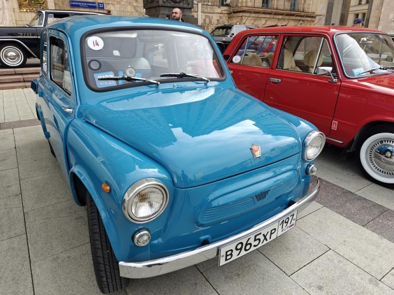 Diplorally, 26 сентября 2026: голубой Запорожец и красный «Москвич» на площади перед зданием с надписью «СМОЛЕНСКАЯ-СЕВЕРНАЯ 32»