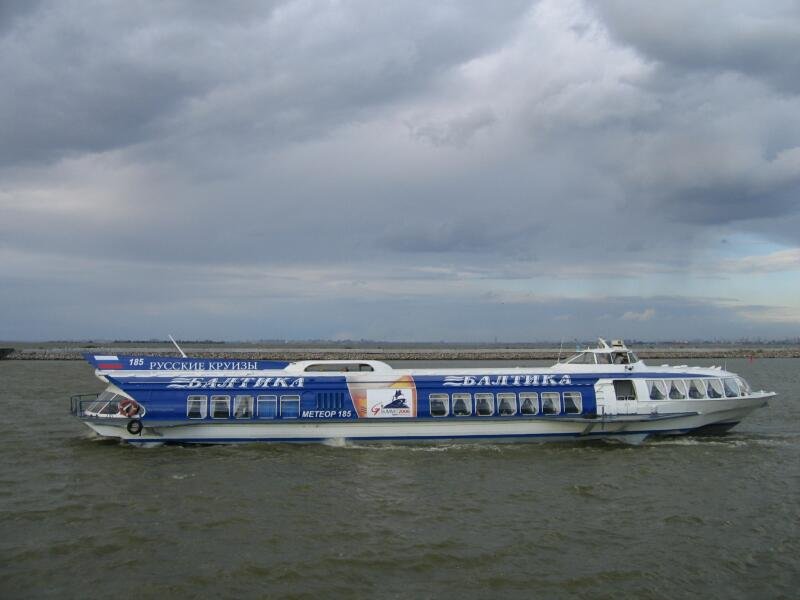 Сине-белый пассажирский теплоход «Балтика» с надписью «Метеор 185» на воде при облачной погоде