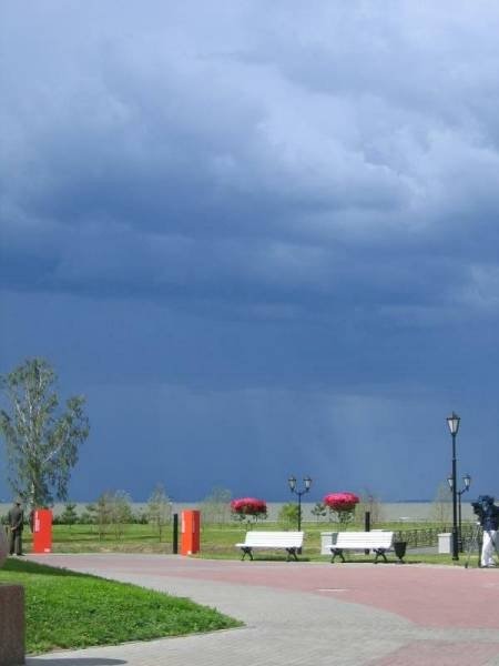 Парк у воды под тёмным небом с грозовыми облаками