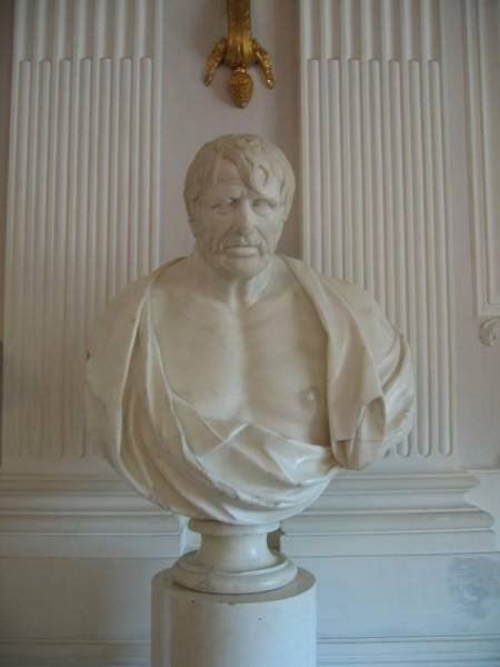 Бюст в Гатчине, 2006: мраморная фигура на белом постаменте у рельефной стены