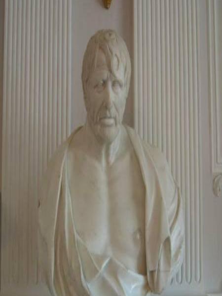 Бюст в Гатчине, 2006: мраморная фигура на белом постаменте у рельефной стены