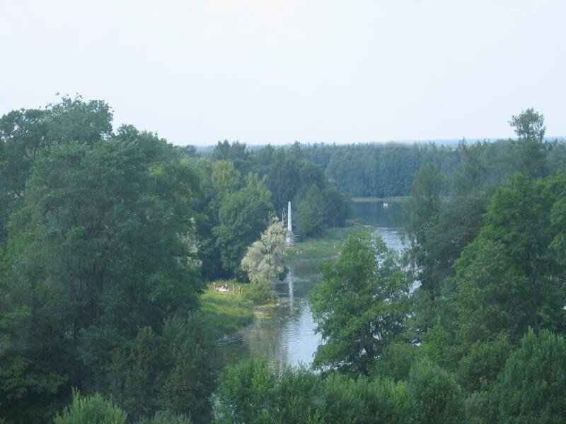 Река, окружённая густым лесом и зелёными берегами с памятником