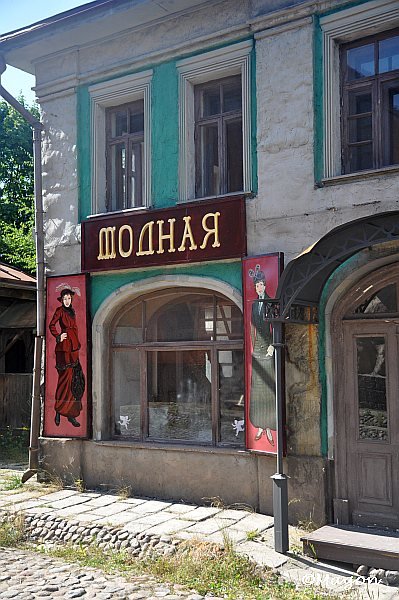 Двухэтажное здание с вывеской «ЯНДОШ» и историческими плакатами
