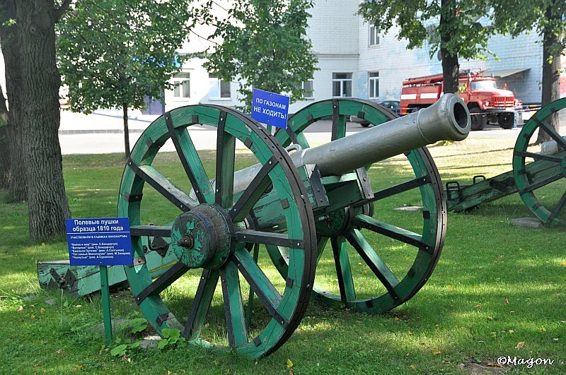 Зелёная пушка 1810 года на зелёной лужайке у деревьев