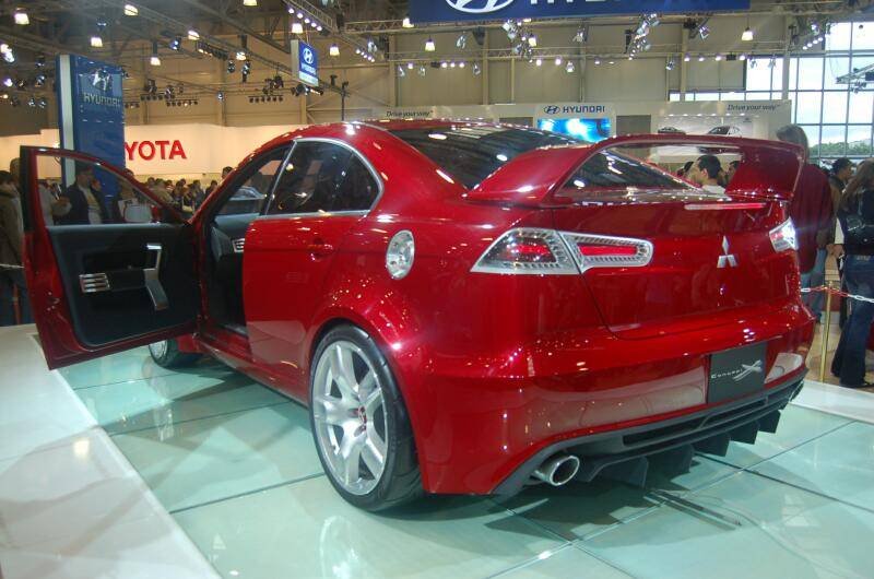 Красный спортивный автомобиль Mitsubishi на автосалоне с открытыми дверями
