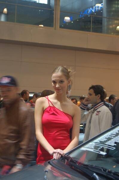 Motorshow 2006: красная модель у передней части автомобиля в зале выставки