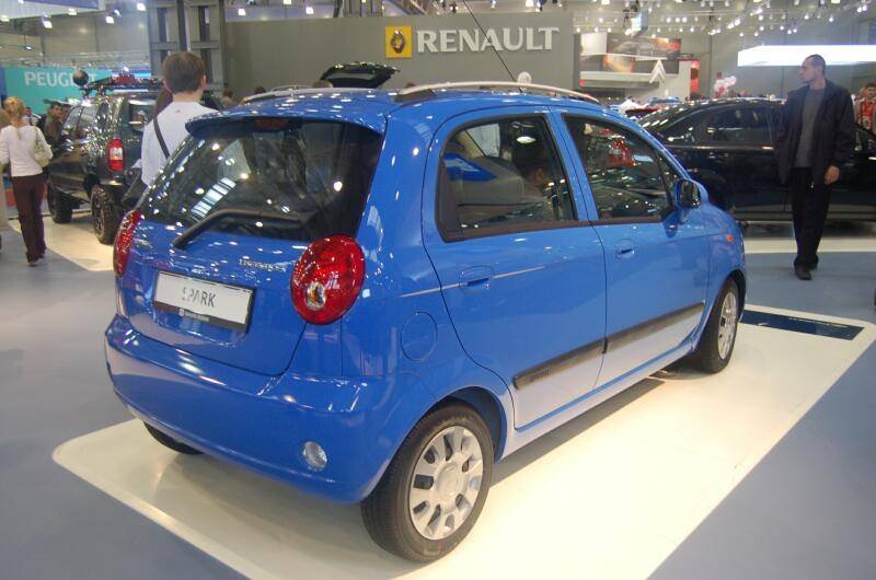 Синий автомобиль Chevrolet Spark на автосалоне с вывеской Renault
