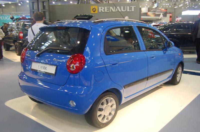Синий автомобиль Chevrolet Spark на автосалоне с вывеской Renault