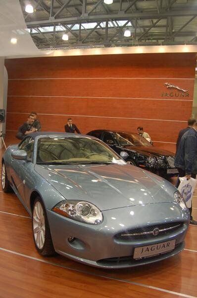 Моторшоу-2006: серебристый Jaguar XKR на фоне деревянной стены с логотипом