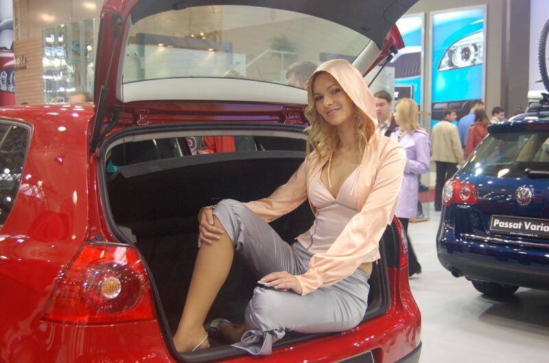 Моторшоу-2006: женщина в розовом капюшоне сидит в багажнике красного Volkswagen