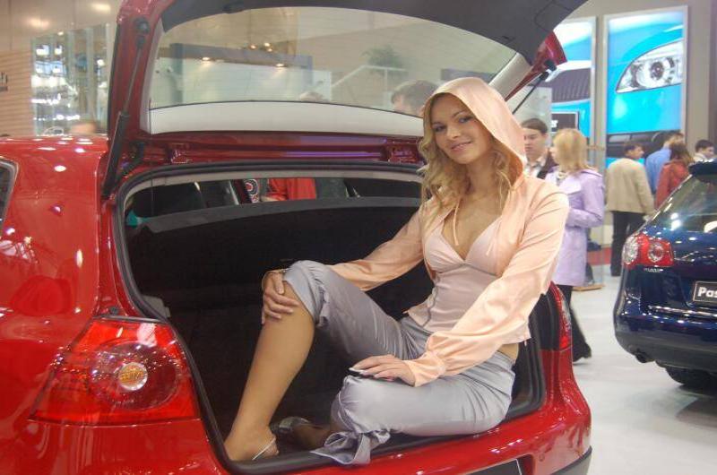 Моторшоу-2006: женщина в розовом капюшоне сидит в багажнике красного Volkswagen