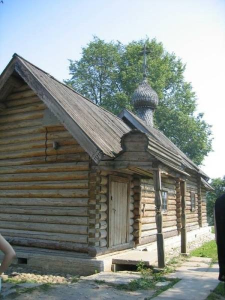 Деревянная церковь с куполом и крестом на фоне зеленых деревьев