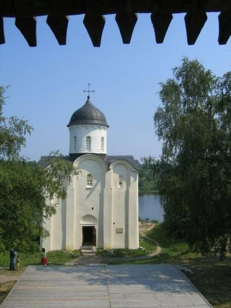 Белокаменная церковь с черным куполом у воды под деревянным навесом