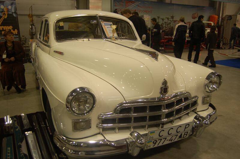 Oldtimer 06 2: белый ГАЗ-12 в зале выставки с трофеем на капоте