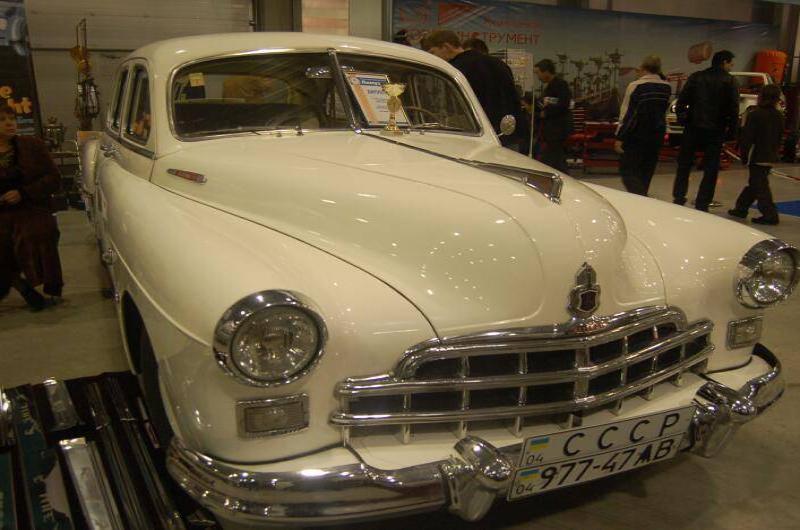 Oldtimer 06 2: белый ГАЗ-12 в зале выставки с трофеем на капоте
