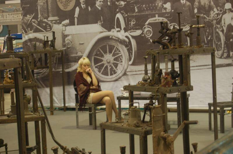Oldtimer 06 2: женщина в бордовой накидке между ржавыми станками и исторической фотопанелью