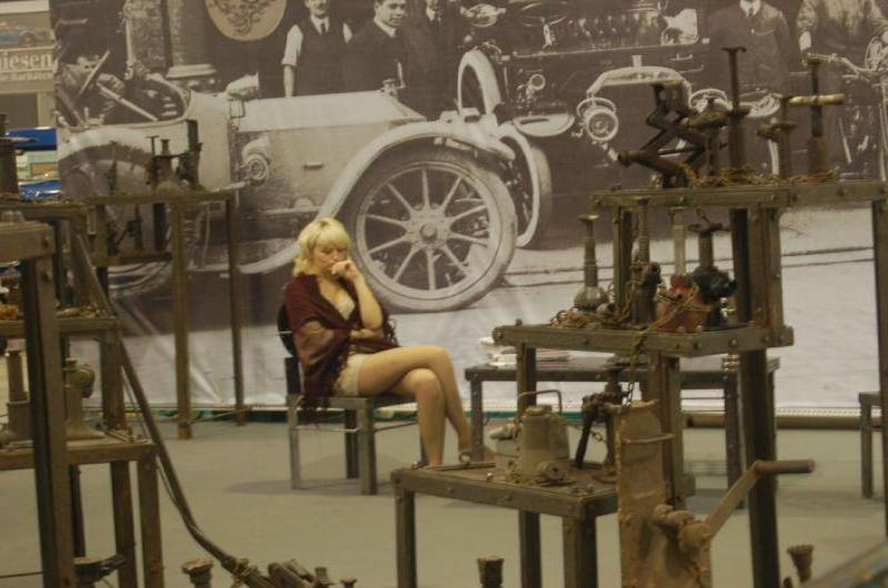 Oldtimer 06 2: женщина в бордовой накидке между ржавыми станками и исторической фотопанелью