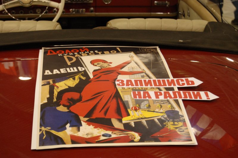 Ретро-плакат «Долой кухонное рабство!» на капоте красного автомобиля