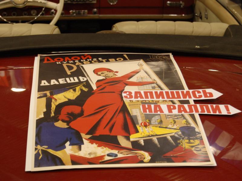 Ретро-плакат «Долой кухонное рабство!» на капоте красного автомобиля
