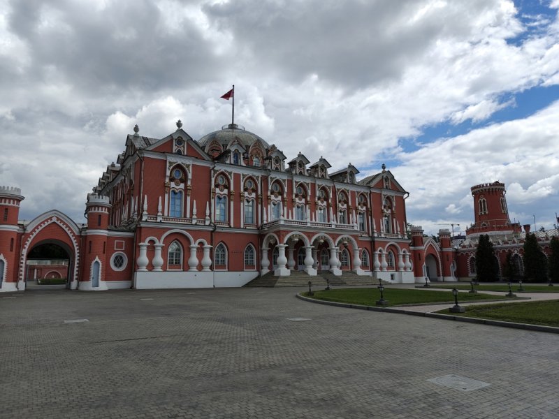 Здание Петровского путевого дворца: красный кирпич, белые колонны и флаг над куполом