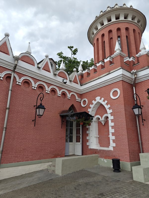 Петровский путевой дворец: красно-белая башня с арочным входом и фонарями