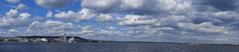Саратов с Волги: мост через реку, городской силуэт и облака над водой