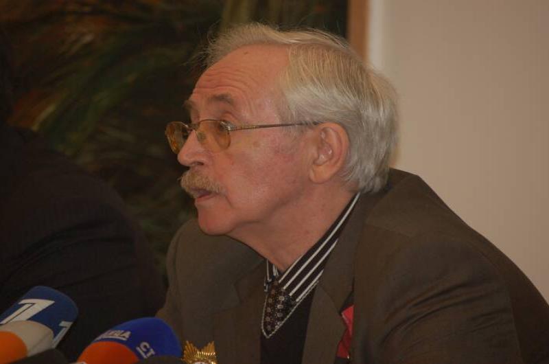Памятник Шерлоку Холмсу в России: мужчина у микрофонов перед зелёной стеной