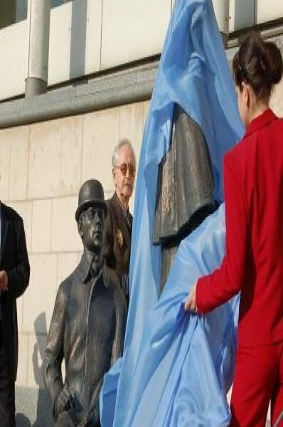 Установка памятника в синей ткани на фоне современного здания