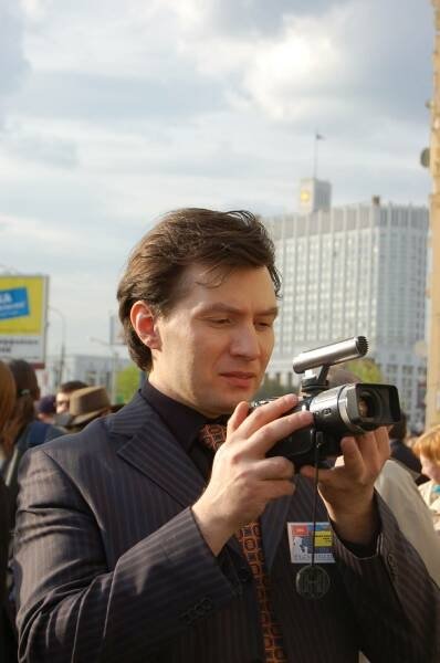 Мужчина в пиджаке с видеокамерой на улице города