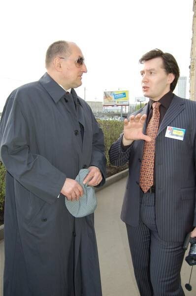Два мужчины в деловой одежде беседуют на улице возле здания
