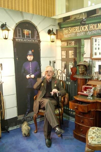 Памятник Шерлоку Холмсу в Москве: мужчина в кресле у вывески «The Sherlock Holmes»