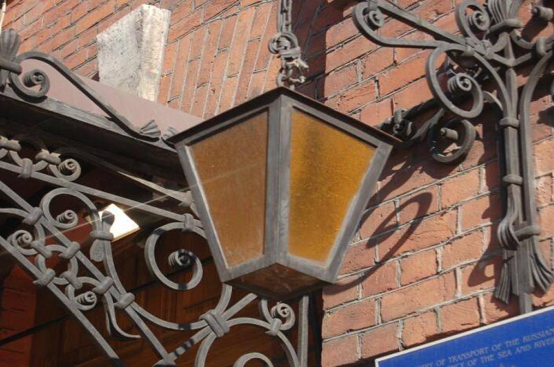 Фонарь у кирпичной стены в СПб: оранжевое стекло и кованые узоры