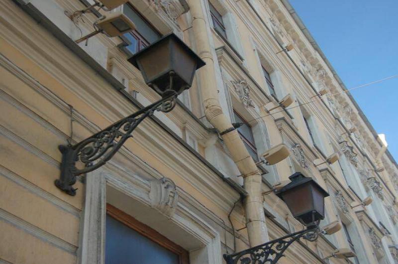 Светильники на фасаде здания в СПб: узорчатые кронштейны и желтая штукатурка