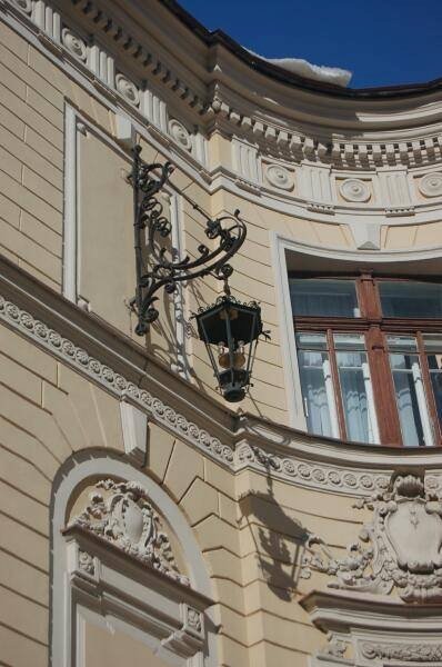Фонарь на углу здания в СПб: кованая ручка и лепнина барокко