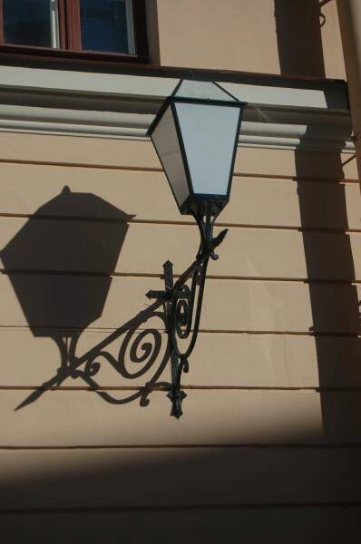Уличный фонарь на фасаде в Spb Flashlamps: кованая подставка и тень от лампы