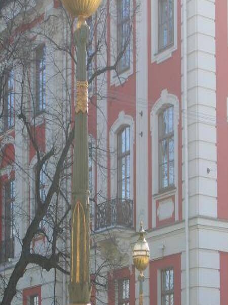 Золотистые фонари на фоне красно-белого здания в Санкт-Петербурге
