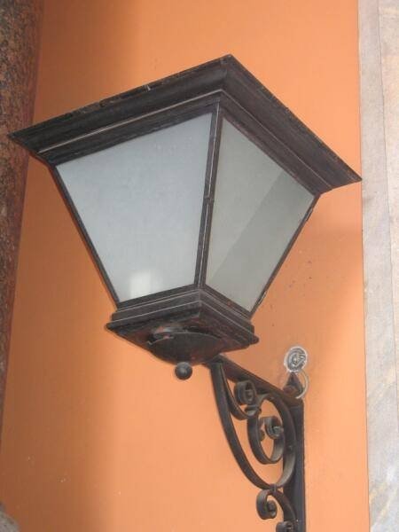 Фонарь у оранжевой стены в Spb Flashlamps: кованая подвеска и матовое стекло